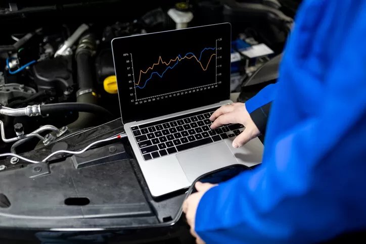 RoadReady technician reviewing live diagnostic data on a laptop under the hood